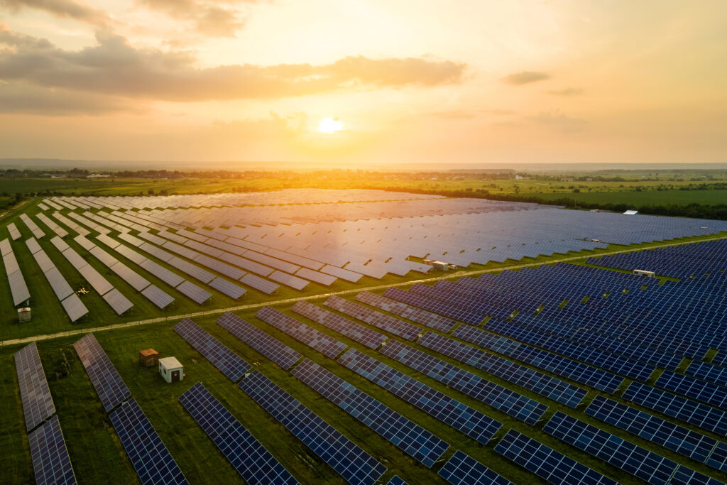 Aerial view of large sustainable electrical power plant with many rows of solar photovoltaic panels for producing clean ecological electric energy in evening. Renewable electricity with zero emission concept. Eine große PV-Freiflächenanlage in der Natur erzeugt Energie.