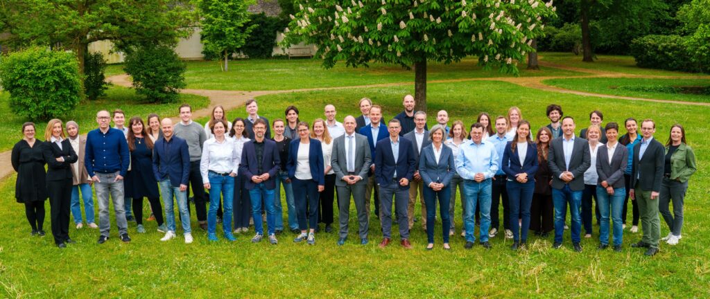 Das gesamte Team der Stiftung Umweltenergierecht präsentiert sich vor einer grünen Parkfläche.